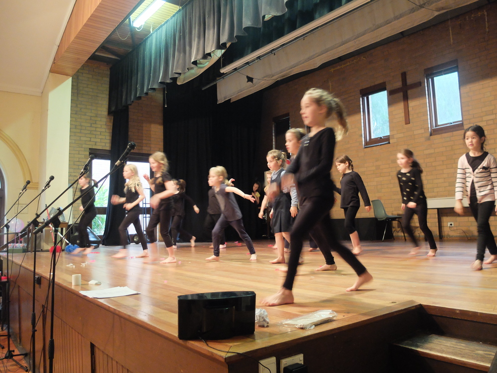 Primary students creating an ensemble movement performance on stage